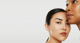 A young woman, face close to the expert's, demonstrates skincare techniques, showcasing attentive care and expertise.