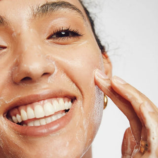 A close-up shot of a woman's face, showcasing the application of facial cream. The cream appears smooth and luxurious, evenly distributed across her skin, leaving a subtle, healthy glow. Her expression is serene, conveying a sense of calm and self-care. The lighting is soft and flattering, highlighting the texture and tone of her skin.