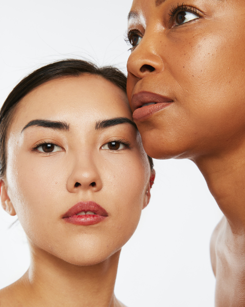 A woman with glowing, clear skin against a warm neutral background  representing the transformative results of Skin by Brownlee and Co. skincare for melanated skin